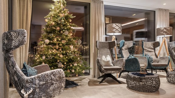 Ein modern gestalteter Wohnraum mit bequemen Sesseln und einem geschmückten Weihnachtsbaum. Große Fenster sorgen für viel Licht und eine gemütliche Atmosphäre. - MYALPS Tirol - Oetz