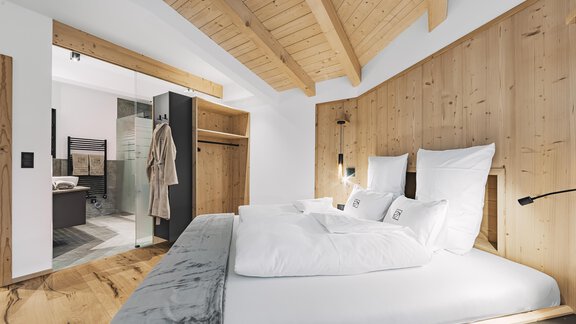 Ein modernes Schlafzimmer mit einem gemütlichen Holzdesign. Die Ausstattung umfasst ein großes Bett und einen direkten Zugang zum Badezimmer. - See das Ferienhaus - Oetz