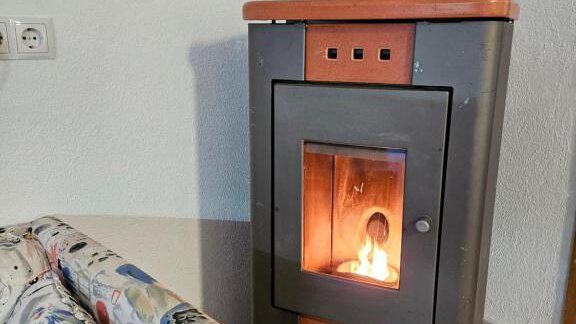 A modern stove stands in a cozy room. Next to the stove is a colorful couch. - Appartement Harmony - Sautens