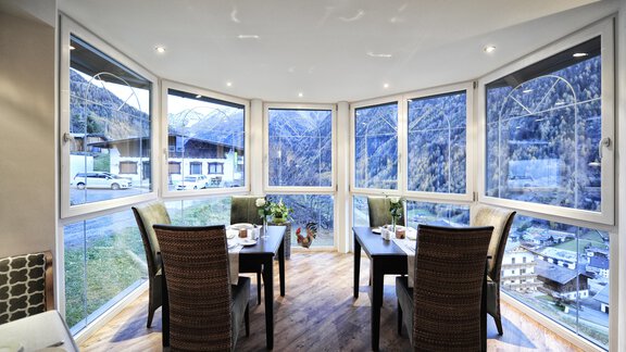 A modern dining area with large windows and a beautiful view of the mountains. The room is cozy and invitingly furnished. - Alp Resort Tiroler Adler - Sölden
