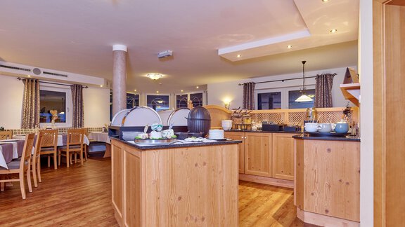 An inviting breakfast area with wooden furniture and a bright, friendly atmosphere. Various food and drinks are available on the tables. - Alp Resort Tiroler Adler - Sölden