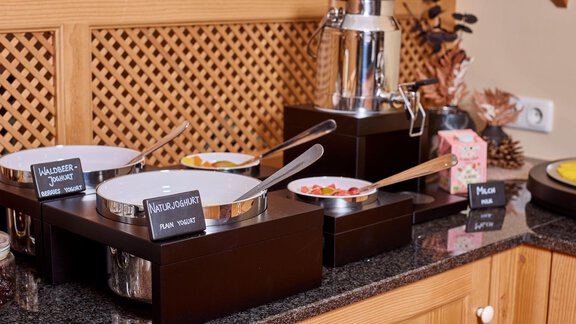 A buffet with various dishes in white bowls. There are labels for the individual dishes. - Alp Resort Tiroler Adler - Sölden