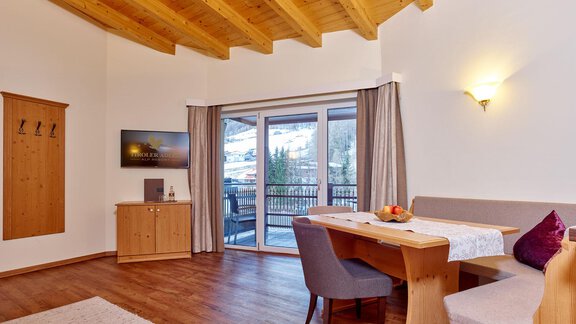 A bright, cozy room with wooden ceilings and a large window. A dining table with chairs and a TV corner are also visible. - Alp Resort Tiroler Adler - Sölden