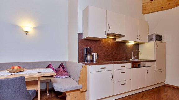 A modern kitchen unit with a bright wooden ceiling and a cozy seating area. The room is well-lit and feels inviting. - Alp Resort Tiroler Adler - Sölden