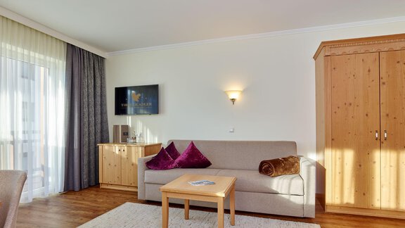 A cozy living room with a sofa, a table, and wooden cabinets. The light is bright and the space feels inviting. - Alp Resort Tiroler Adler - Sölden