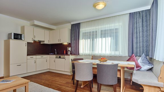 A bright, modern kitchen with a dining area and wooden flooring. There are four chairs at the table, and the windows let in a lot of light. - Alp Resort Tiroler Adler - Sölden