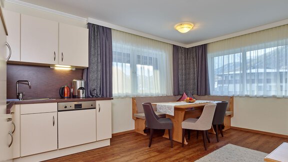 A modern kitchenette with a table and chairs in a bright room. Large windows let in plenty of light and give the room a cheerful atmosphere. - Alp Resort Tiroler Adler - Sölden