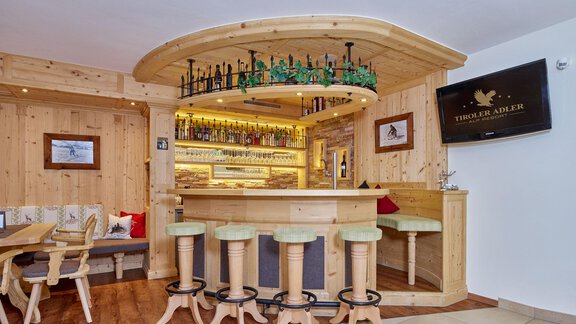 A cozy bar with wooden paneling and a central bar counter. The atmosphere is warm and inviting, perfect for relaxing. - Alp Resort Tiroler Adler - Sölden