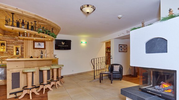 A cozy bar with wooden shelves and chairs. In the background, there is a fireplace that creates a warm atmosphere. - Alp Resort Tiroler Adler - Sölden