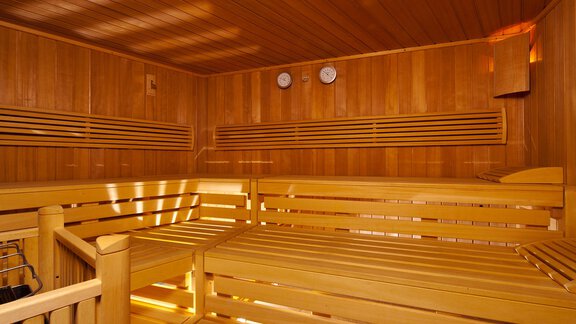 A clean sauna with bright wood and benches. There are two wall clocks and a pleasant atmosphere. - Alp Resort Tiroler Adler - Sölden