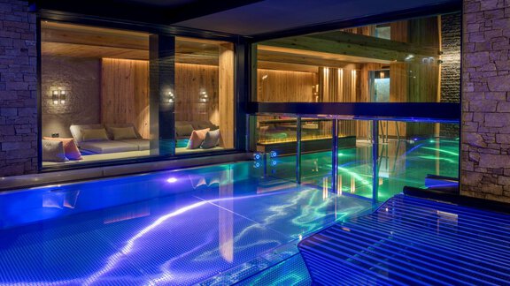 Ein eleganter Innenraum mit einem Pool und sanftem, schimmerndem Wasser. Die Atmosphäre ist entspannend und modern, mit stilvoller Beleuchtung. - Alpengasthof Grüner - Sölden