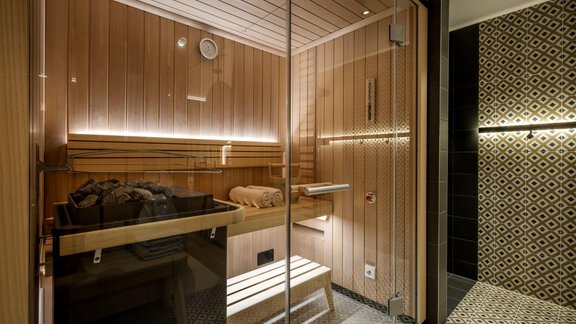 Eine moderne Sauna mit Holzvertäfelung und Glaswänden. Der Raum bietet eine entspannende Atmosphäre mit sanfter Beleuchtung. - Alpengasthof Grüner - Sölden