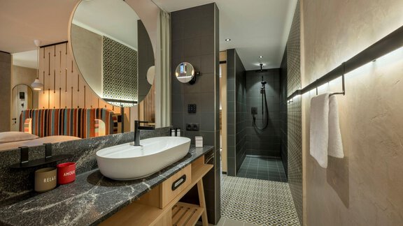 Ein modernes Badezimmer mit einer eleganten Waschbeckenkonsole und einer großen Dusche. Die Einrichtung ist stilvoll und gut beleuchtet, mit schönen Fliesen. - Alpengasthof Grüner - Sölden