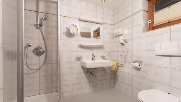A modern bathroom with tiled floor. There is a shower, a sink, and a toilet. - Alpenliebe - Sölden