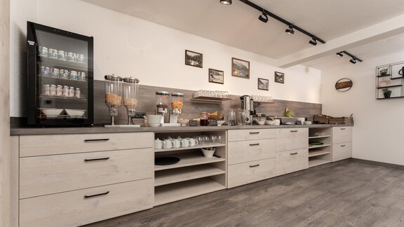A modern kitchen with a wood look and various storage cabinets. On the work surface are jars and breakfast ingredients. - Alpenliebe - Sölden