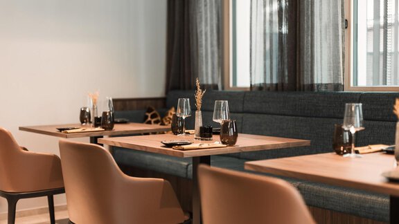 A stylish restaurant with modern tables and chairs. The decor is bright and inviting, with large windows and elegant accessories. - AlpenParks The Secret Sölden - Sölden