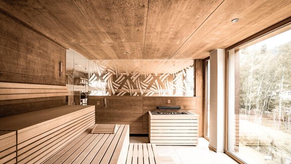 A modern sauna with wooden walls and benches. Large windows provide a view of the nature outside. - AlpenParks The Secret Sölden - Sölden