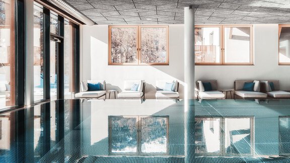 A modern indoor pool with clean lines and inviting loungers. Large windows let in plenty of light and offer a beautiful view. - AlpenParks The Secret Sölden - Sölden