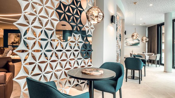 A modern café with stylish, round tables and elegant chairs. The walls are decoratively designed and the lighting is cozy. - AlpenParks The Secret Sölden - Sölden
