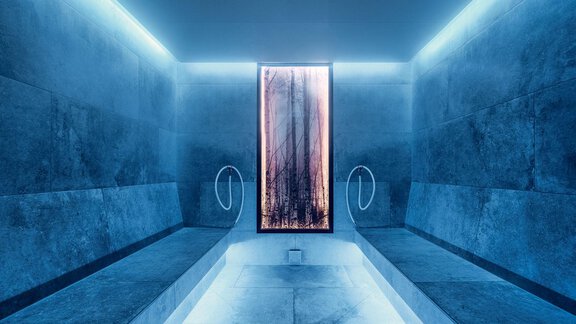 A modernly designed space with blue lights and stone benches. In the middle, there is a large, oval window that creates a calming atmosphere. - AlpenParks The Secret Sölden - Sölden