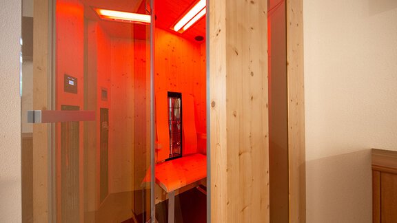 A modern spa with wooden panels and reddish lighting. The room conveys relaxation and well-being. - Alpensweet - Sölden
