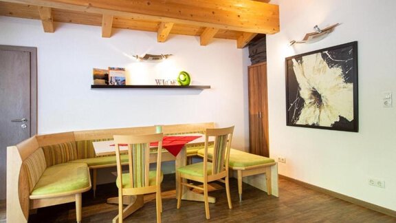 An inviting dining area with a wooden ceiling and modern furnishings. The cozy seating area accommodates several people and is decorated with a piece of artwork. - Alpensweet - Sölden