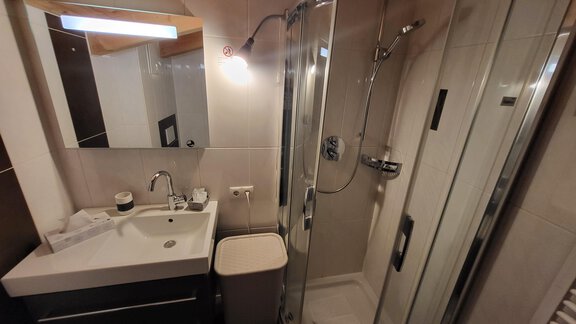 A modern bathroom with a shower cubicle and a sink. The room is bright and well-furnished. - Alpensweet - Sölden