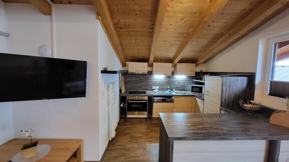 A modern kitchen with wooden ceilings and various appliances. The room feels bright and inviting. - Alpensweet - Sölden