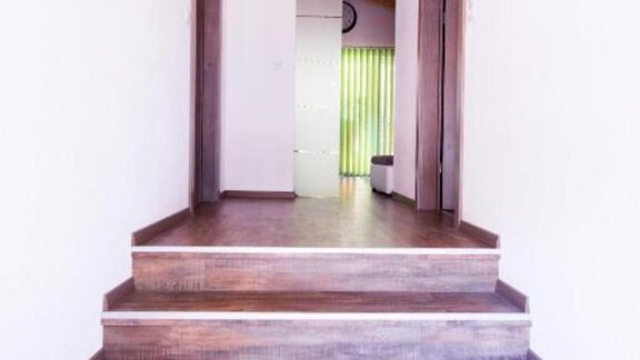 A bright hallway with wooden stairs and white walls. In the background, two doors and plenty of daylight are visible. - Alpensweet - Sölden