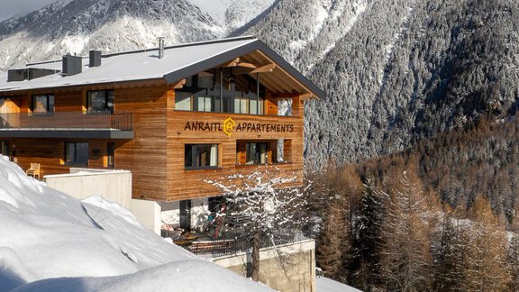 A wooden house in the mountains, surrounded by snowy landscapes. The sky is clear and the mountain world shines in the winter sun. - Anraitl Appartements Sölden - Sölden