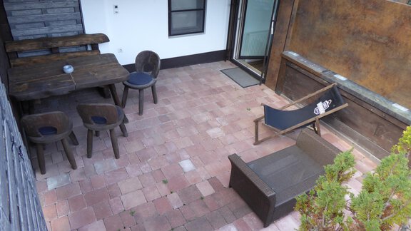 Eine gemütliche Terrasse mit einem Tisch und Stühlen aus Holz. Es gibt eine Liege und Pflanzen, die den Raum verschönern. - Apart 55 - Sölden