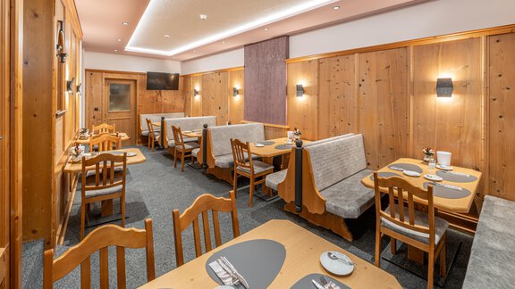 A cozy restaurant with wooden walls and warm lighting. The tables are neatly set and invite you to linger. - Apart Hotel Garni Alt Kaisers - Sölden