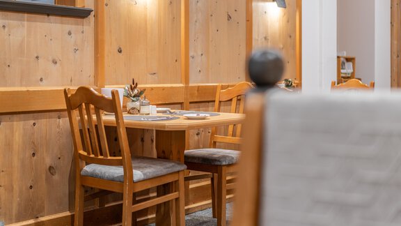 A cozy table with chairs in a warm, paneled wood room. The atmosphere is inviting and perfect for a relaxed meal. - Apart Hotel Garni Alt Kaisers - Sölden