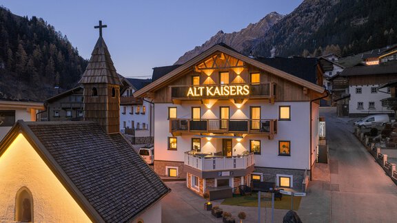 A cozy hotel named "Alt Kaisers" in the mountains. The facade is illuminated, and the surroundings feature a picturesque mountain landscape. - Apart Hotel Garni Alt Kaisers - Sölden