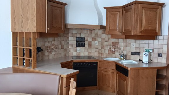 A modern wooden kitchen with an L-shaped layout. It features a stove, a sink, and attractive tiles. - Apart Romed - Sölden