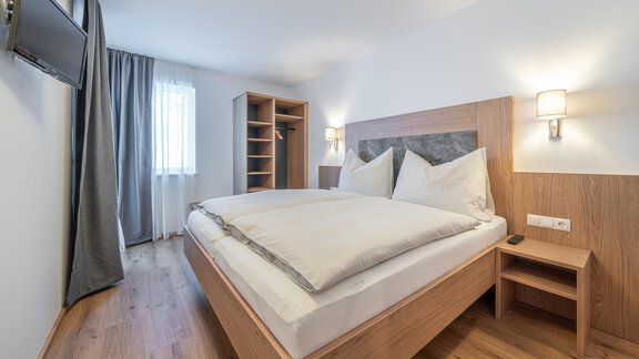 A modern bedroom with a large bed and wooden furniture. The room is bright and invites relaxation. - Apart Sonnenbichl - Sölden