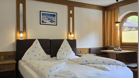 A cozy hotel room with a double bed and two pillows. The room is tastefully furnished and has a window with a view outside. - Apart Tyrolis - Sölden