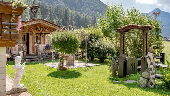 A picturesque garden with a wooden gazebo and beautiful greenery. In the background, mountains are visible, completing the landscape. - Apart Wiesengrund - Sölden
