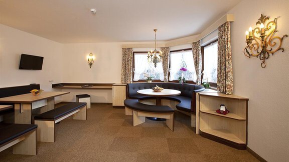 A cozy room with seating and large windows. A round table in the middle invites you to linger. - Appartement Alpin - Sölden