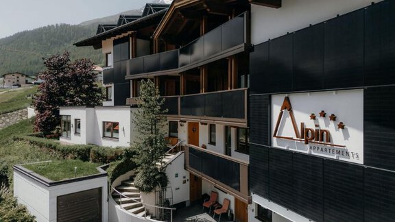 A modern building named "Alpin Appartements" in a mountainous setting. The architecture is stylish and there is a beautifully designed outdoor area. - Appartement Alpin - Sölden