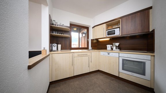 A modern kitchen with wooden shelves and a large window. It is well equipped with appliances like a refrigerator and a microwave. - Appartement Alpin - Sölden