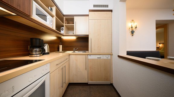 A modern kitchen with wooden shelves and built-in appliances. The atmosphere is bright and inviting. - Appartement Alpin - Sölden