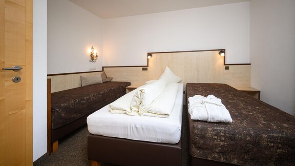 A simple and modern room with two single beds and neutral colors. There is a warm atmosphere created by the wall lighting and the wooden details. - Appartement Alpin - Sölden