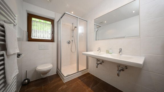 A modern bathroom with a shower cubicle and a large mirror. The walls are light tiled and there is a pleasant atmosphere. - Appartement Alpin - Sölden