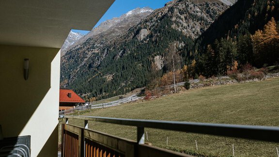 A balcony with a view of the mountains and a green meadow. The sky is clear and blue. - Appartement Bergbach Sölden - Sölden