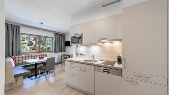 A modern kitchen with bright cabinets and a dining area. The room is friendly and well-lit, overlooking a beautiful outdoor space. - Appartement Cristallo - Sölden