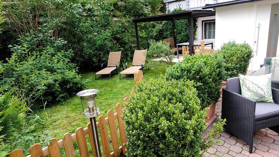 A cozy garden with green plants and two loungers. The seating area invites you to relax. - Appartement Gehörde Sölden - Sölden