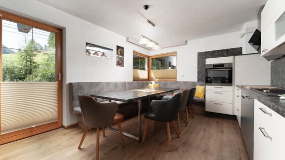 A modern kitchen with a large table and elegant chairs. Plenty of daylight streams through the windows onto the bright walls. - Appartement Gehörde Sölden - Sölden