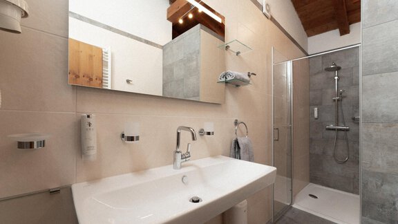 A modern bathroom with a large shower and an elegant sink. The walls are in light tones, and the wooden ceiling creates a cozy atmosphere. - Appartement Gehörde Sölden - Sölden