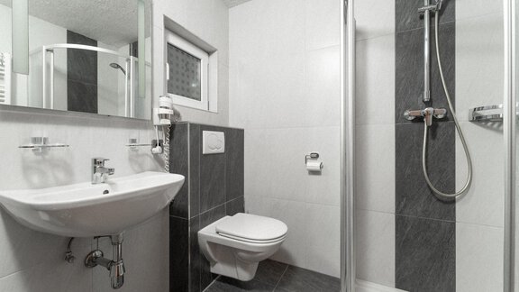 A modern bathroom with a shower, sink, and toilet. The walls are designed in neutral colors. - Appartement Gehörde Sölden - Sölden